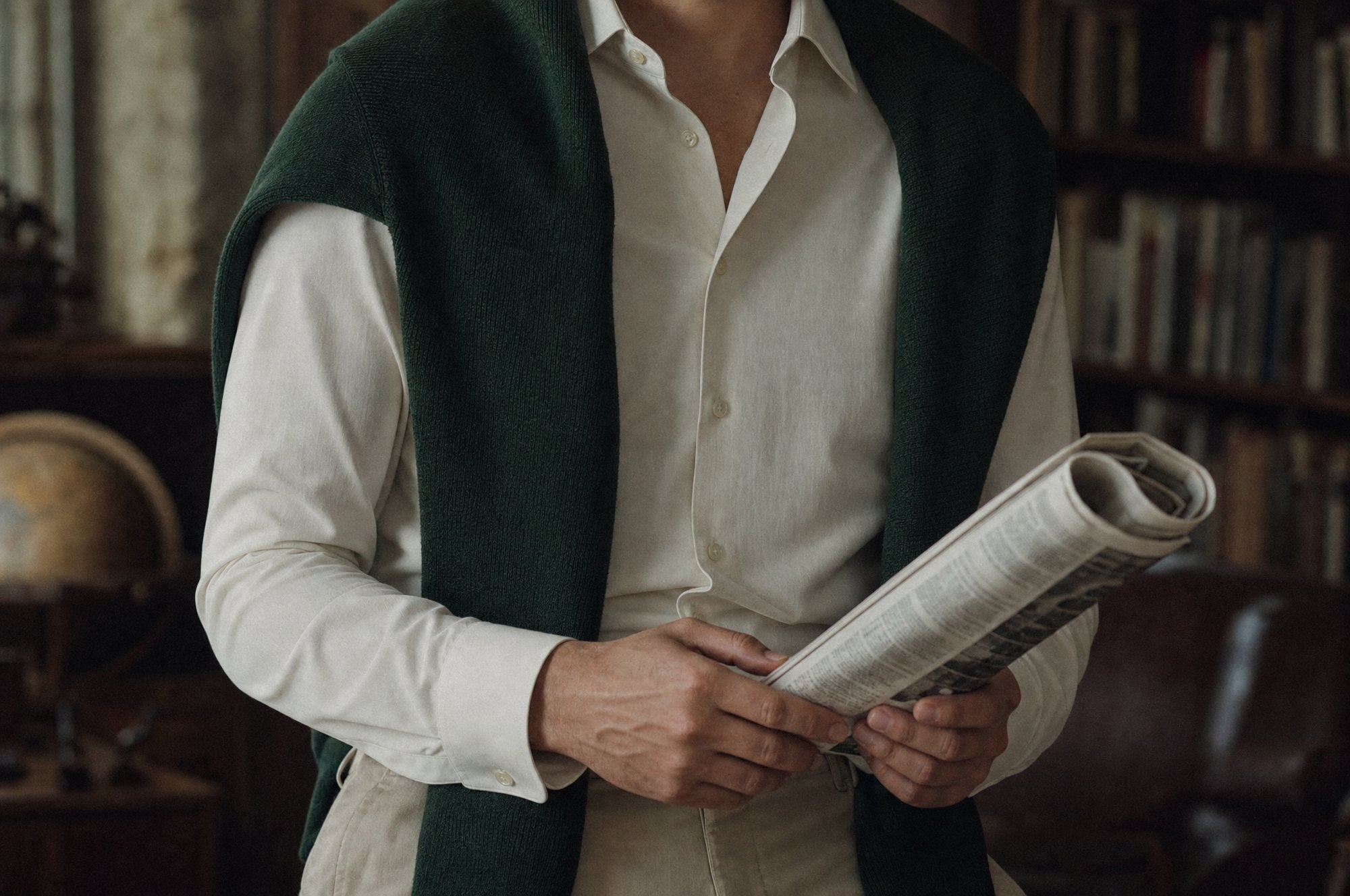 Cream shirt with a green knit draped over the shoulders